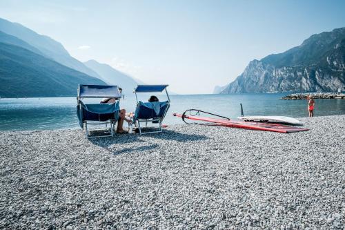 a couple of people sitting in chairs on a beach at Hotel Villa Alberta in Nago-Torbole
