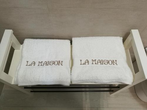 2 serviettes blanches assises sur une étagère dans une salle de bains dans l'établissement La Maison, à Margherita di Savoia