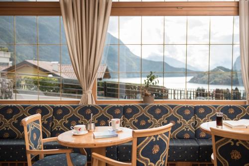 a restaurant with a couch and tables and windows at Hotel Lory - Molveno - Dolomiti in Molveno