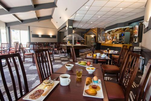 a restaurant with tables and chairs with food on them at Ibis Château-Thierry in Essômes-sur-Marne