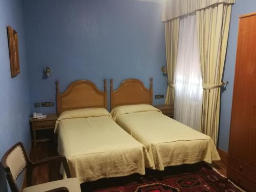 two beds in a bedroom with blue walls and a window at Hotel Xabier in Javier