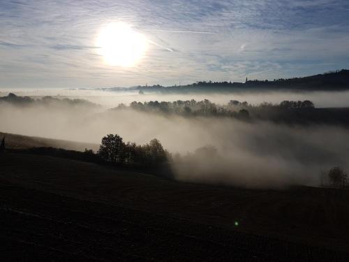a foggy field with the sun in the background at Locanda Sensi in Rivergaro