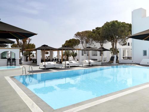 a pool at a hotel with chairs and umbrellas at Kalisti Hotel & Suites in Fira