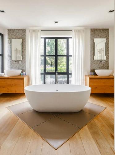 La salle de bains est pourvue d'une grande baignoire blanche et de 2 lavabos. dans l'établissement Domaine de Bramafam, à Plascassier