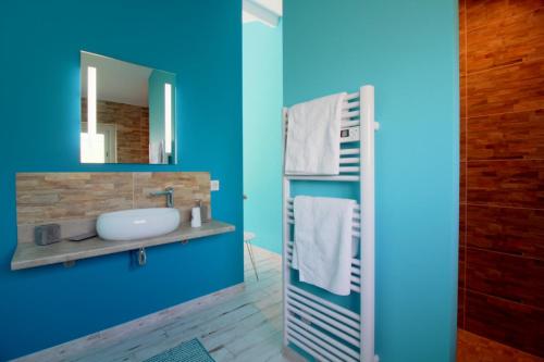 a blue bathroom with a sink and a mirror at La Mancine Laulan in Jau-Dignac-et-Loirac