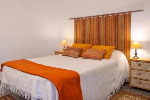a bedroom with a large white bed with orange pillows at Casa do Loreto in Ponta Delgada
