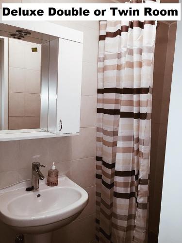 a bathroom with a sink and a shower curtain at Guest House Edem II in Sarajevo