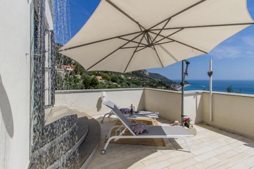 a chair and an umbrella on a balcony with the ocean at Villa Degli Ulivi B&B in Finale Ligure