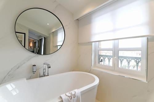a white bathroom with a tub and a mirror at Hôtel Alchimy in Albi