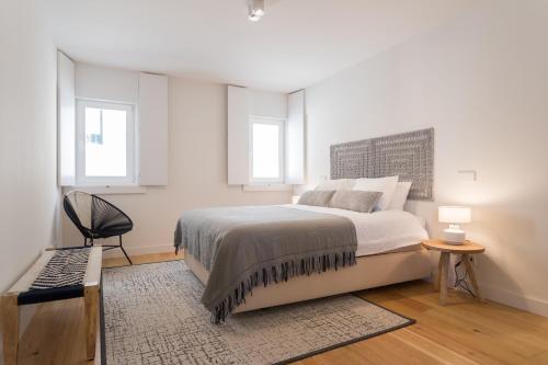 ein weißes Schlafzimmer mit einem Bett und zwei Fenstern in der Unterkunft FLH Martim Moniz Luxus Flat in Lissabon