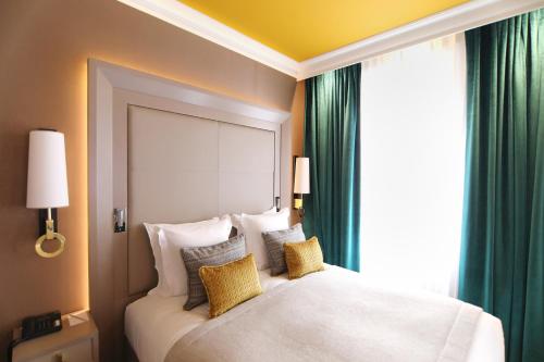 a bedroom with a large white bed with green curtains at Hôtel Alchimy in Albi