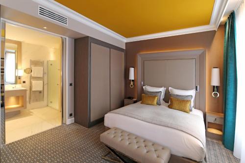 a bedroom with a large bed and a bathroom at Hôtel Alchimy in Albi
