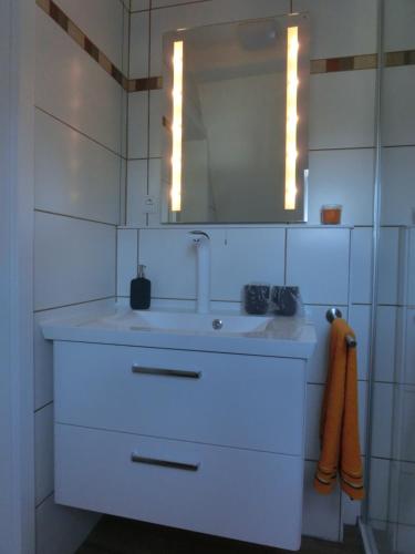 ein weißes Badezimmer mit einem Waschbecken und einem Spiegel in der Unterkunft Ferienhaus Cartoonwerkstatt in Kapellen-Drusweiler