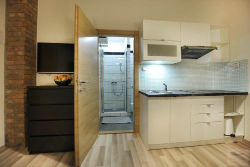 a kitchen with white cabinets and a glass shower at Apartmány Kukučín in Košice