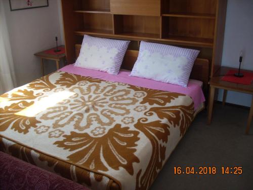 a bed with a brown and white blanket and pillows at Apartment at Sea in Lovran