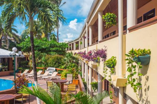 een resort met een zwembad en tafels en stoelen bij Best Western Plus Belize Biltmore Plaza in Belize City