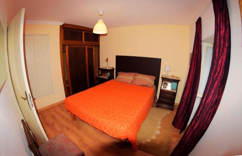 a bedroom with a bed with an orange bedspread at Moinho do Prado in Vila Nova de Cerveira