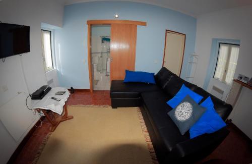 a living room with a black couch and blue pillows at Moinho do Prado in Vila Nova de Cerveira