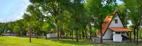 una pequeña casa blanca en un campo con árboles en Cabañas Juan Salvador en Los Reartes