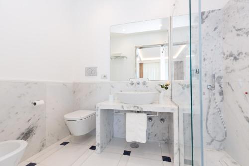 a white bathroom with a sink and a shower at Quattro Passi Relais in Nerano