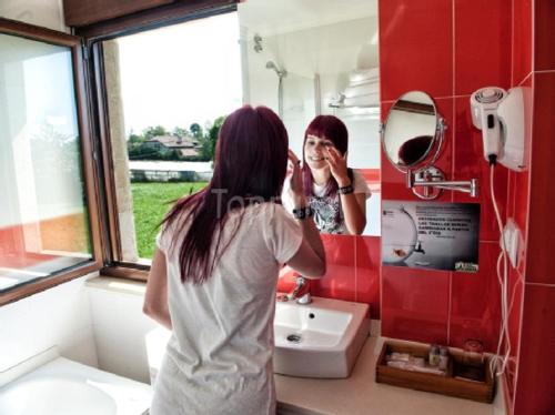 Una donna che guarda il suo riflesso in uno specchio del bagno di Spa Rural Mies de Rubayo a Rubayo