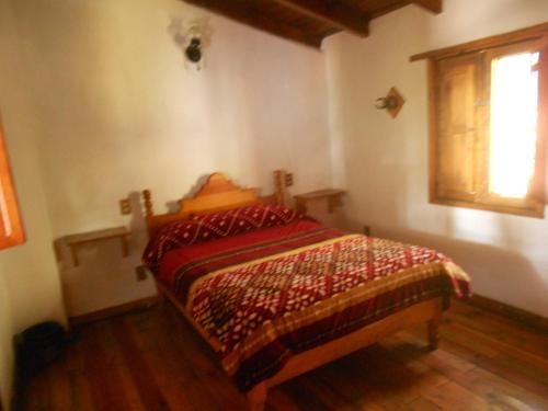 a bedroom with a bed with a comforter and a window at Cabañas los Venados in Mazamitla