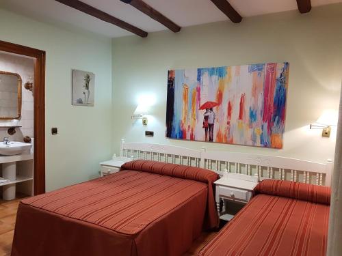 マドリガル・デ・ラ・ベラにあるHosteria Doña Conchiのベッドルーム1室(ベッド2台付)が備わります。壁には絵画が飾られています。