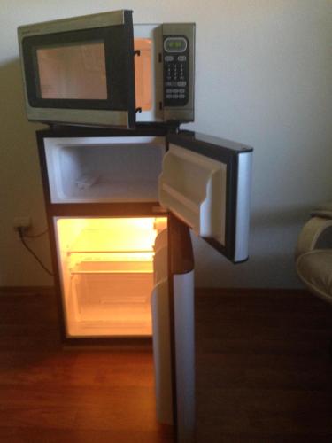 a microwave on a stand with an open refrigerator at Walk to Indian Rocks Beach Exclusive Use of Hot Tub, Pool, BBQ,with Privacy in Largo