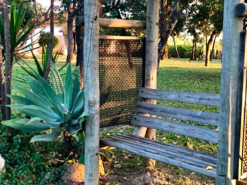 a wooden bench next to a fence with a plant at Mar Doce Boutique Hotel in Três Marias