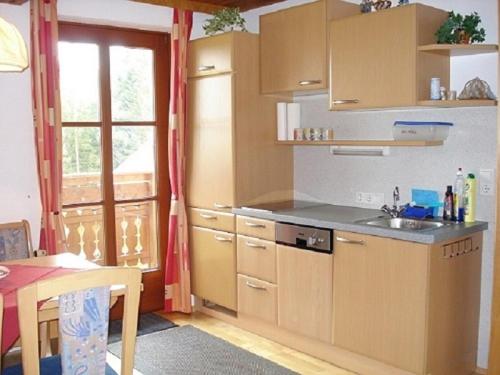 eine Küche mit Holzschränken, einem Tisch und einem Fenster in der Unterkunft Maxgut in Mariapfarr