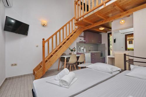 two beds in a room with a staircase and a kitchen at Smaragda Studios Skopelos in Skopelos Town