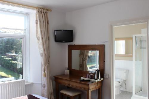 a bathroom with a mirror and a vanity and a window at Invergarry Room Only Guest House For Adults in Windermere
