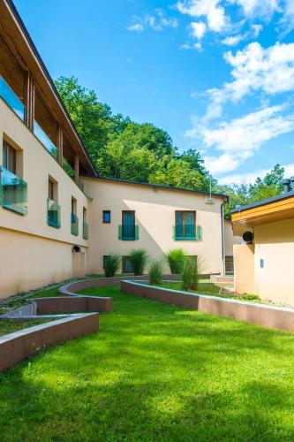 an exterior view of a building with a green yard at Patak Park Hotel Visegrád in Visegrád