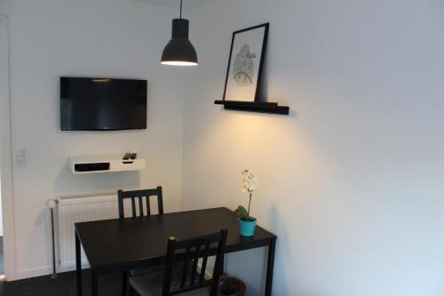 a dining room with a table and a tv on the wall at Close But Quiet in Herlev