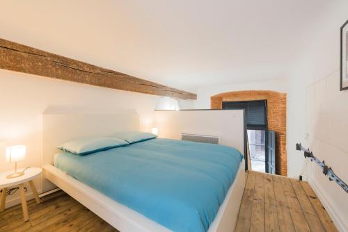 a bedroom with a large bed with blue sheets at Daurade in Toulouse