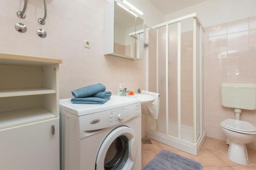 baño con aseo y lavadora blanca en Apartments Radović, en Labin