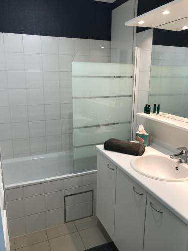 een witte badkamer met een wastafel en een bad bij Appartement dans Résidence les Dunes du Golf in Wimereux