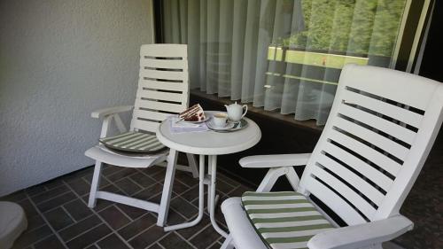 豪富基森安德恩茨的住宿－Café Blaich - Hotel Garni，两把白色椅子和一张桌子,上面有盘子的食物