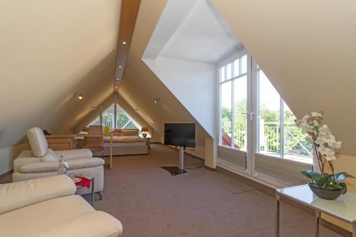 a attic living room with white furniture and large windows at HOTEL am STRAND in Kühlungsborn