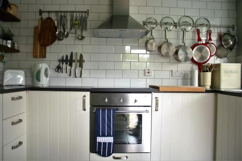 a kitchen with white cabinets and a stove top oven at Mousetrap in Wells next the Sea