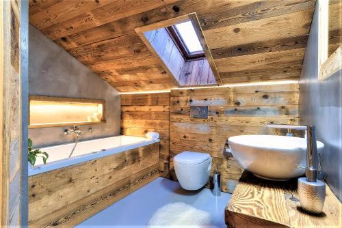 La salle de bains est pourvue de murs en bois, d'une baignoire et d'un lavabo. dans l'établissement Chalet le Petou, à Champéry