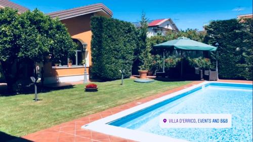 einen Hinterhof mit Pool und Sonnenschirm in der Unterkunft B&B Villa D'Errico in Casapulla