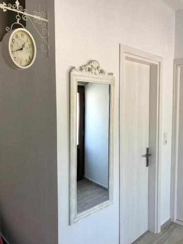 a mirror on a wall with a clock on the wall at BIO Garden Stonehouse in Gonia