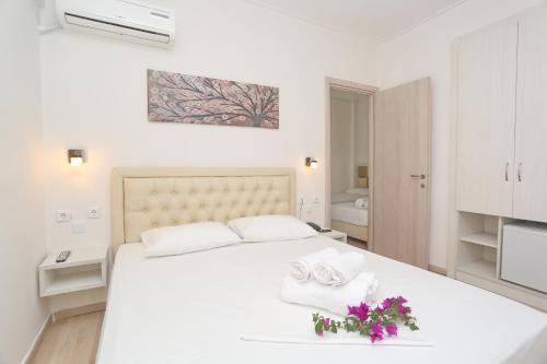 a white bedroom with a large white bed with two towels at Sun Hotel in Polykhrono