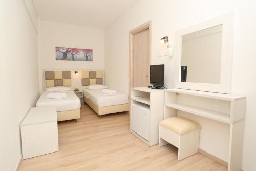 a white room with two beds and a mirror at Sun Hotel in Polykhrono