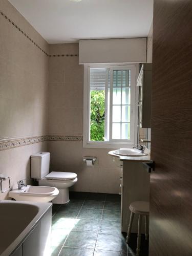 a bathroom with two sinks and a toilet and a window at La casa de Perfecta in Gondomar