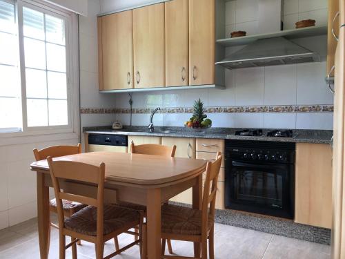 a kitchen with a wooden table and chairs and a stove at La casa de Perfecta in Gondomar
