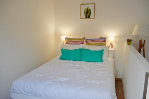 a bedroom with a white bed with colorful pillows at Studio Liberté Plein Centre in Saint-Raphaël