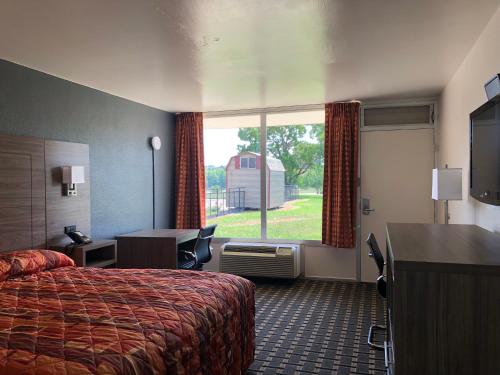 a hotel room with a bed and a desk and a window at Mid Continent Inn in Greenwood