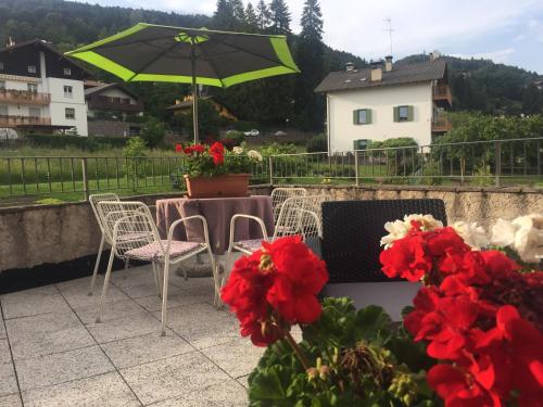 a patio with a table and chairs and an umbrella at CA' del GIACOMINO in Baselga di Pinè